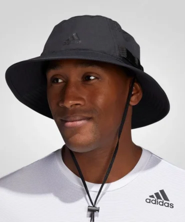 A man wearing a black Adidas Victory 4 bucket hat with a wide brim, drawstring, and Adidas logo. He is also wearing a white Adidas t-shirt.