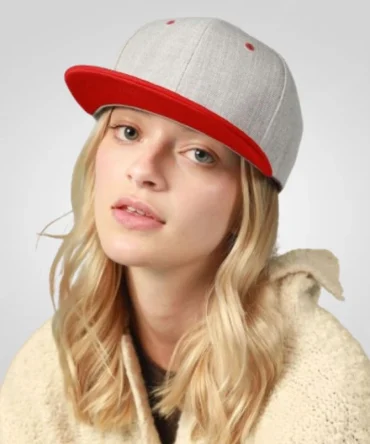 A woman with blonde hair wears a gray flat-bill hat with a red brim.