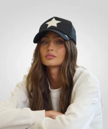 A Baseball Cap young woman with long brown hair poses wearing a black baseball cap with a prominent white star design and a white long-sleeved shirt.