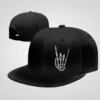 Black snapback hat with white skeleton hand making "rock on" gesture. Flat bill featuring a unique rock and roll skeleton design.